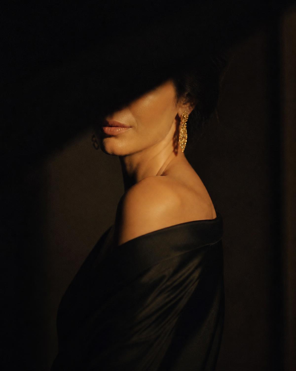 Retrato editorial de mulher elegante em vestido de seda preto, rosto parcialmente em sombra